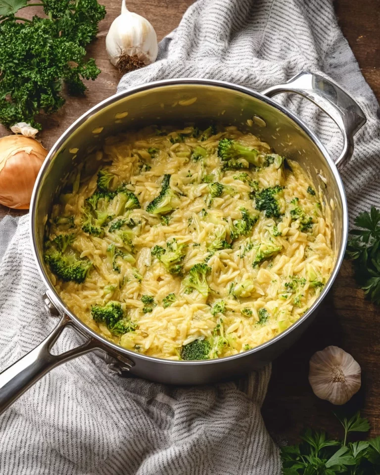 Dish of Cheesy Broccoli Orzo Delight garnished with herbs on a table