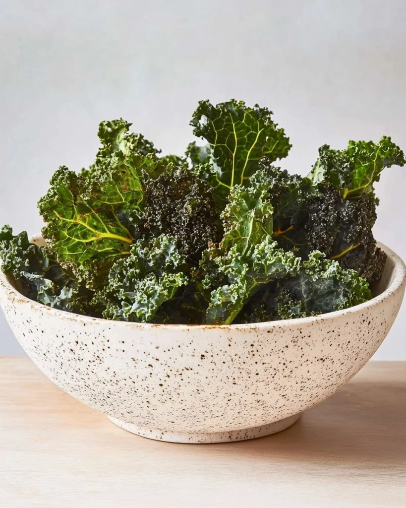Crispy baked kale chips on a white plate, a healthy snack option.