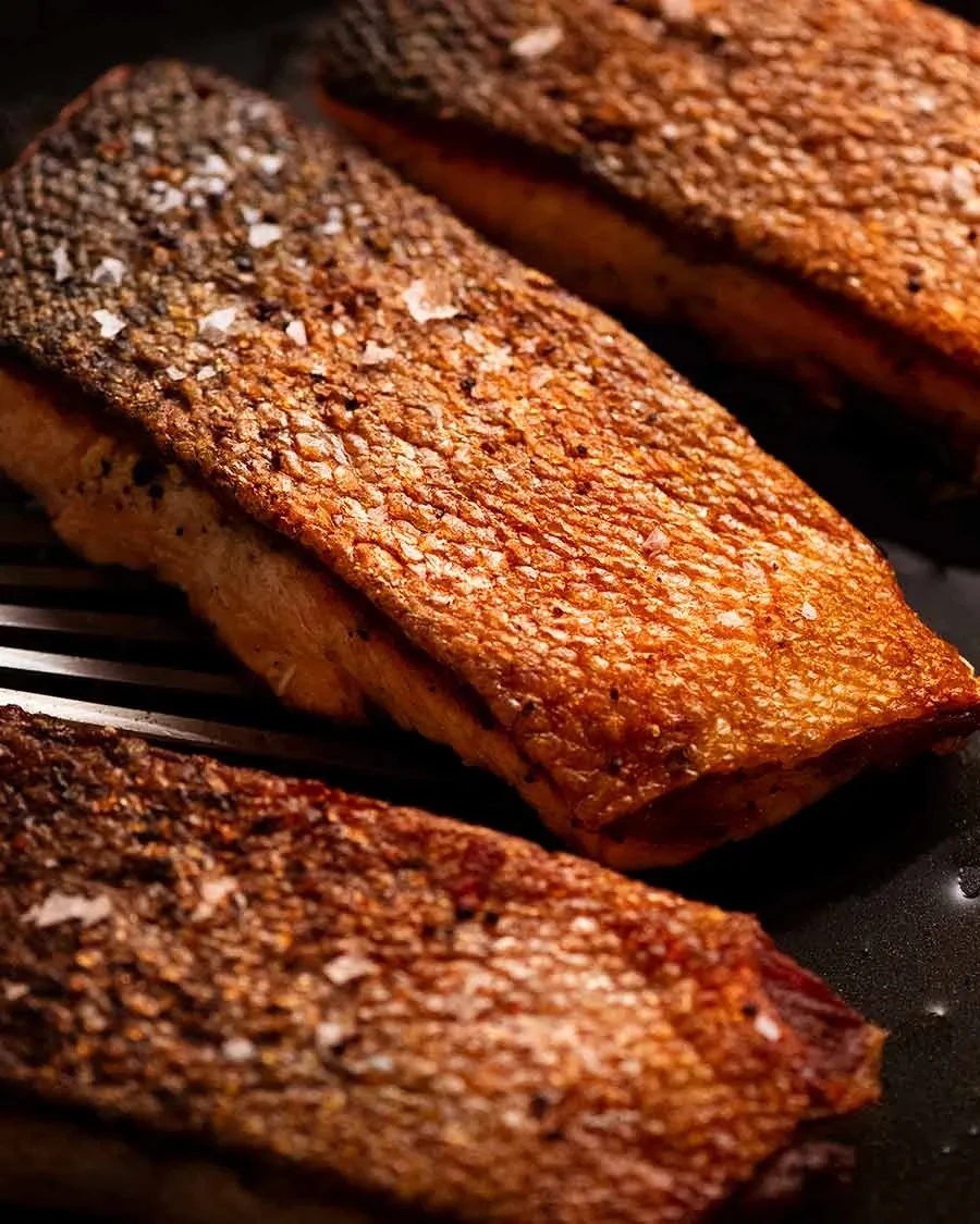Delicious crispy skin salmon served with fresh herbs and lemon slices